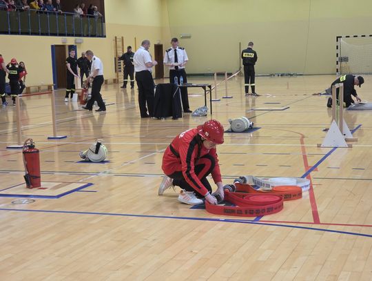 Młodzi strażacy na torze przeszkód w hali. Na trybunach wierni fani